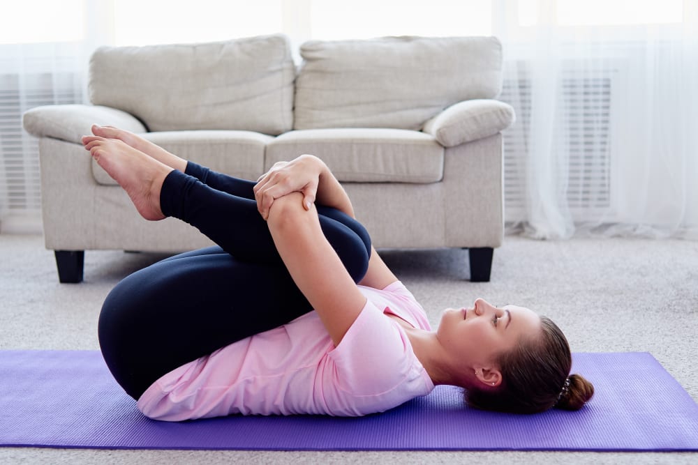 Young woman practicing floor exercise on mat at home