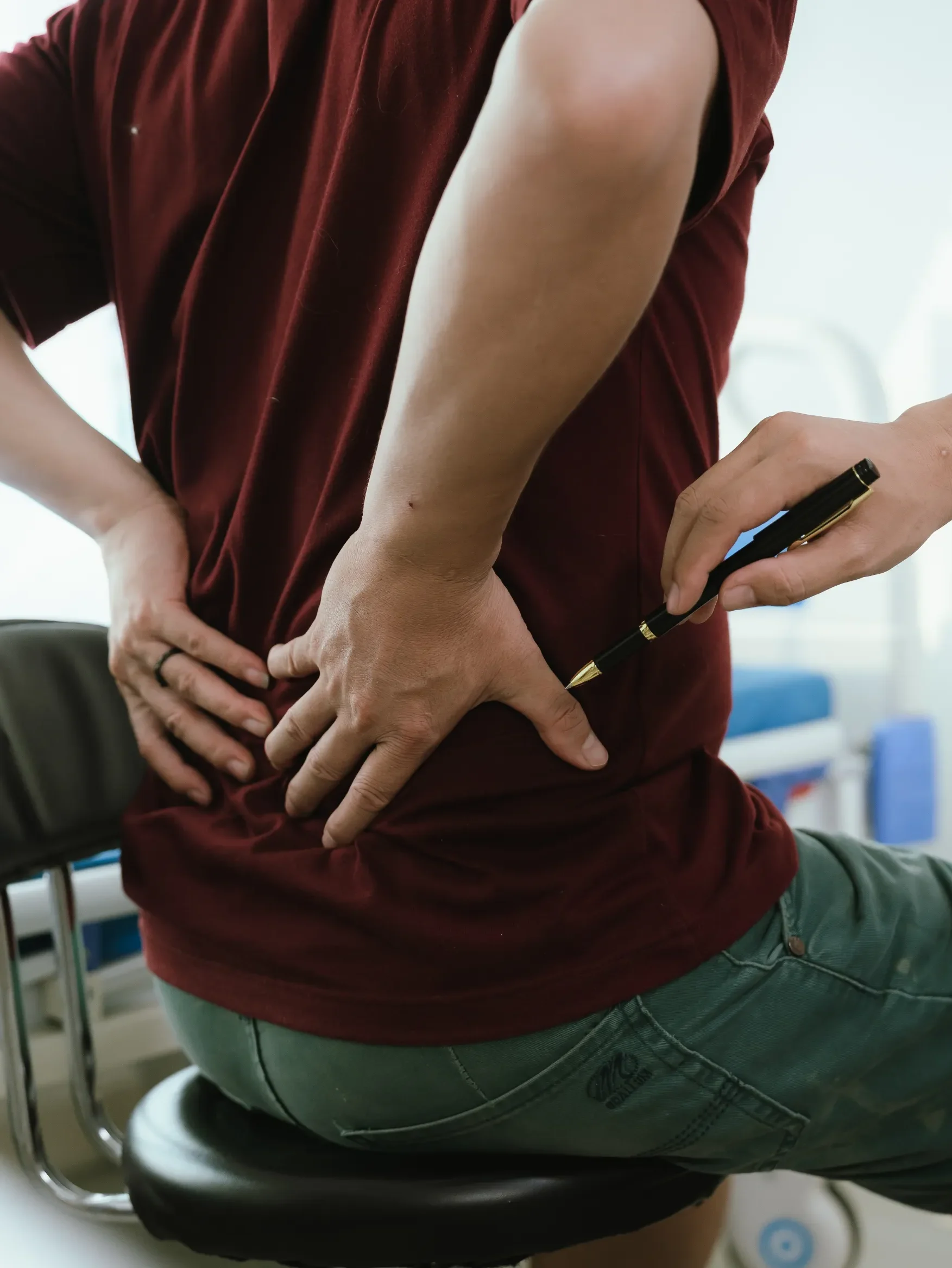 physiotherapist examining their patient's back while the patient demonstrates where their back pain originates